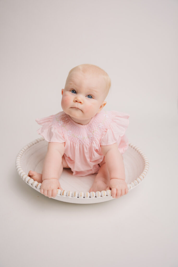 6 month old girl wearing a pink dress from Posh Tots. 