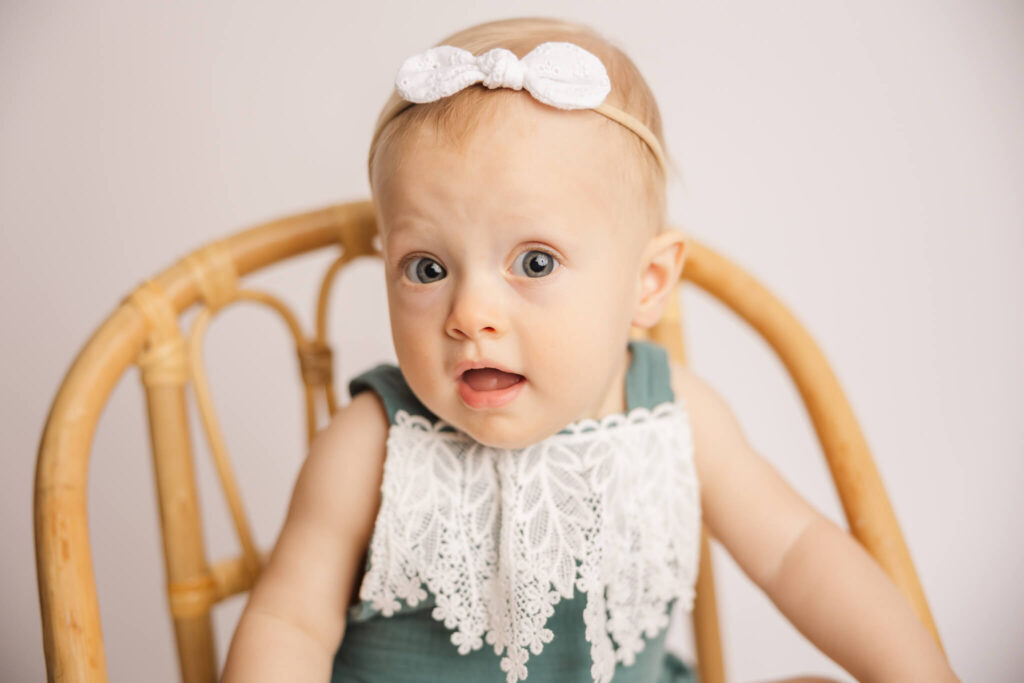 One year old baby girl in a green and white lace outfit during her one year cake smash session in Augusta, GA Dolphin Academy