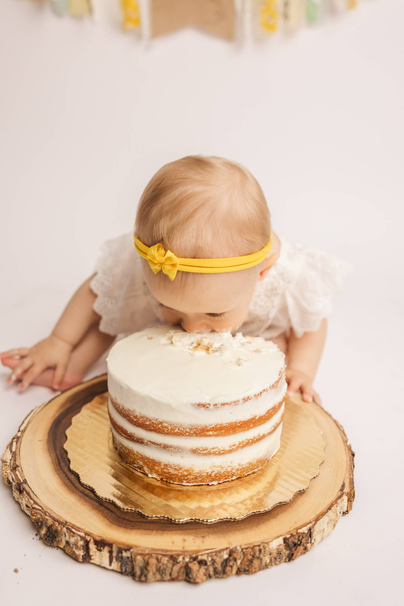 Baby girl enjoying her vanilla cake during her cake smash session.