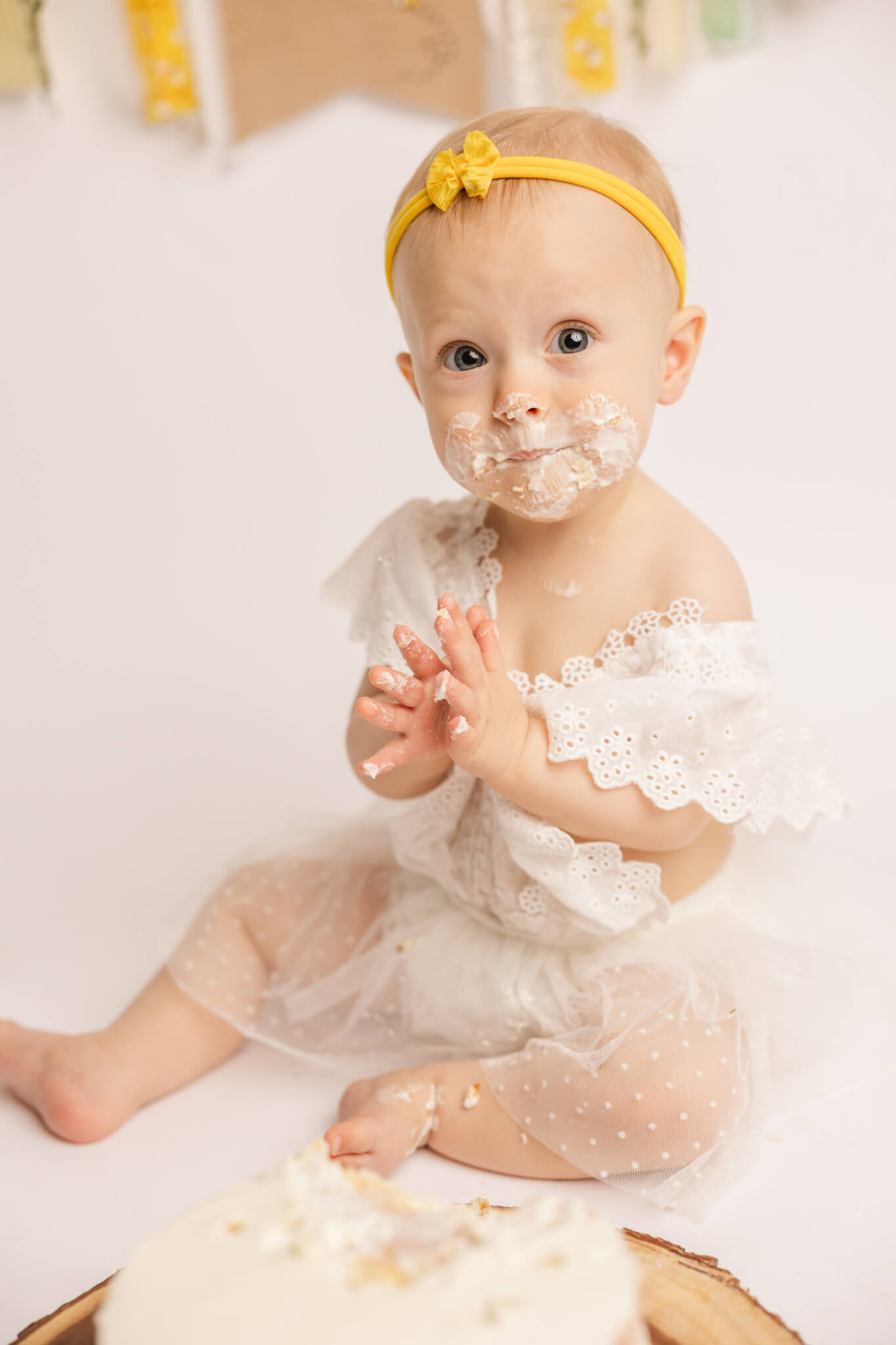 One year old clapping to celebrate her cake during her one year old cake smash session by molly berry photography