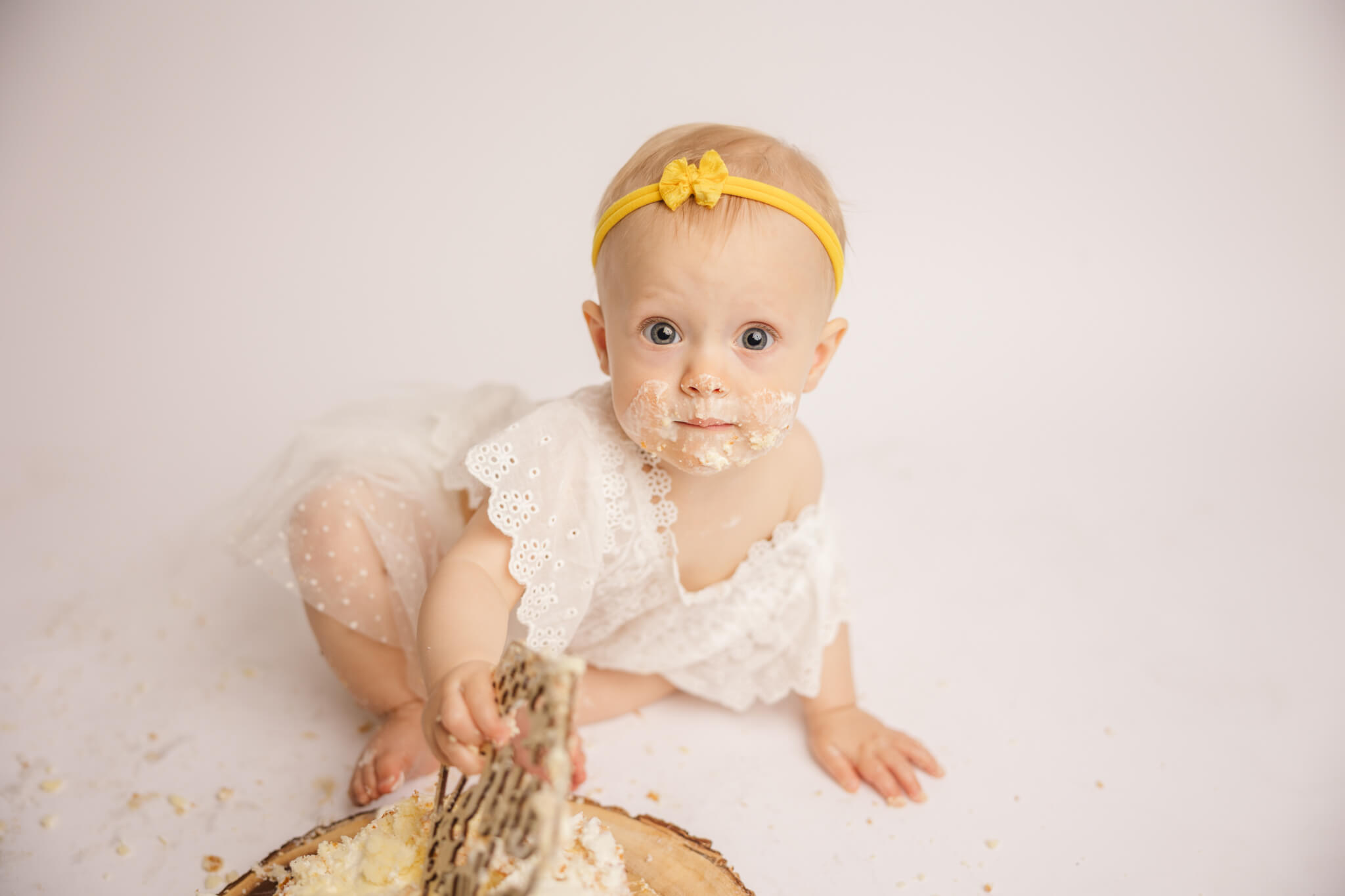 Baby girl playing with her cake topper during her one year session in the studio captured by the augusta cake smash photographer, molly berry