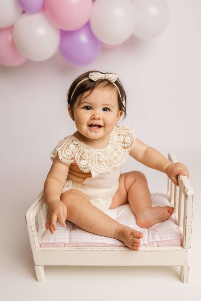One year old sitting on a bed prop during her one year celebration session.