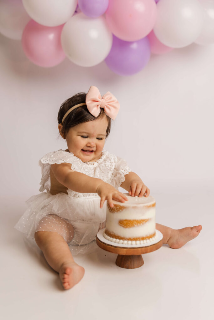 One year old enjoying her naked cake during her milestone and cake smash session with Molly Berry