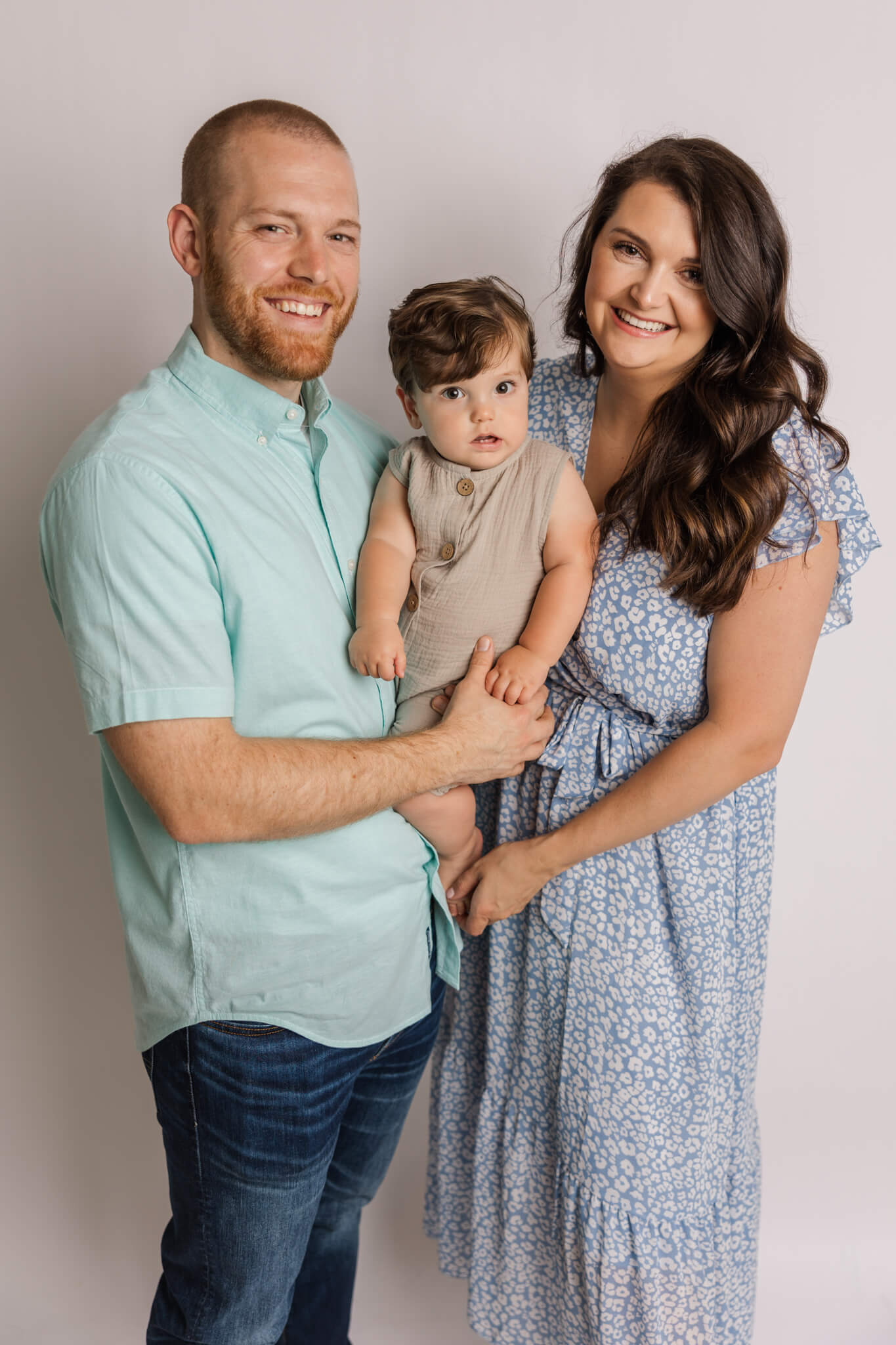 Mom, dad and one year old capture a family photo during their in studio cake smash studio by Molly Berry Photography. The Peppy Poppy