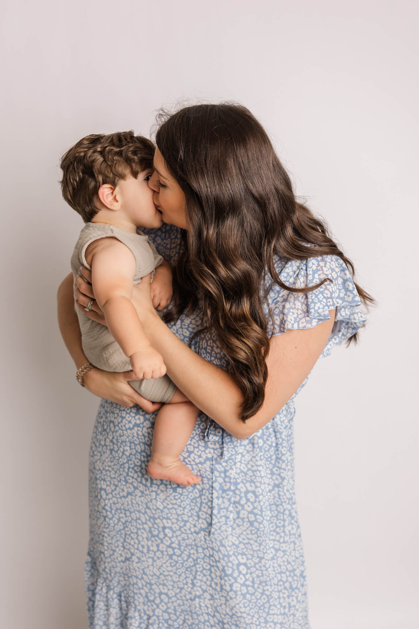 Mom and son share kisses during their family, milestone and cake smash session in the studio by Molly Berry Photography. The Peppy Poppy