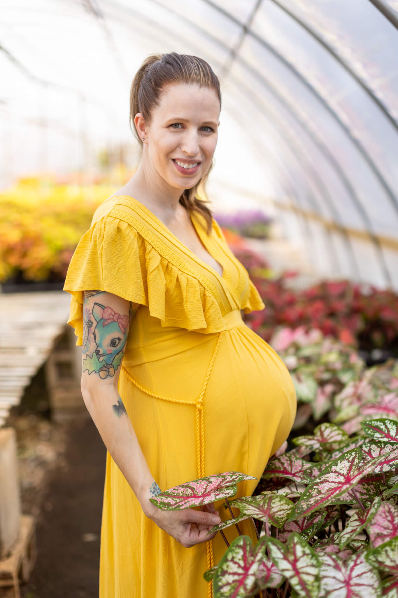 expecting mom playing with a new plant during her maternity session at the greenhouse. obgyn augusta ga