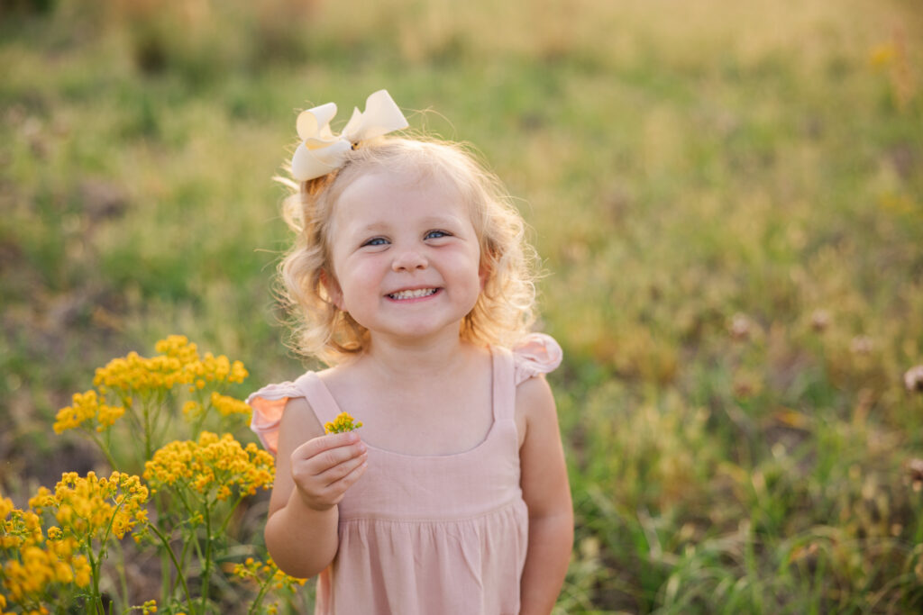 Soon to be big sister posing with a flower during their maternity portraits captured by Molly Berry Photography.