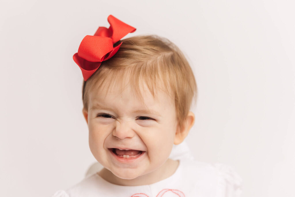One year old wearing a red bow during her one year milestone and cake smash session captured in the studio by Molly Berry