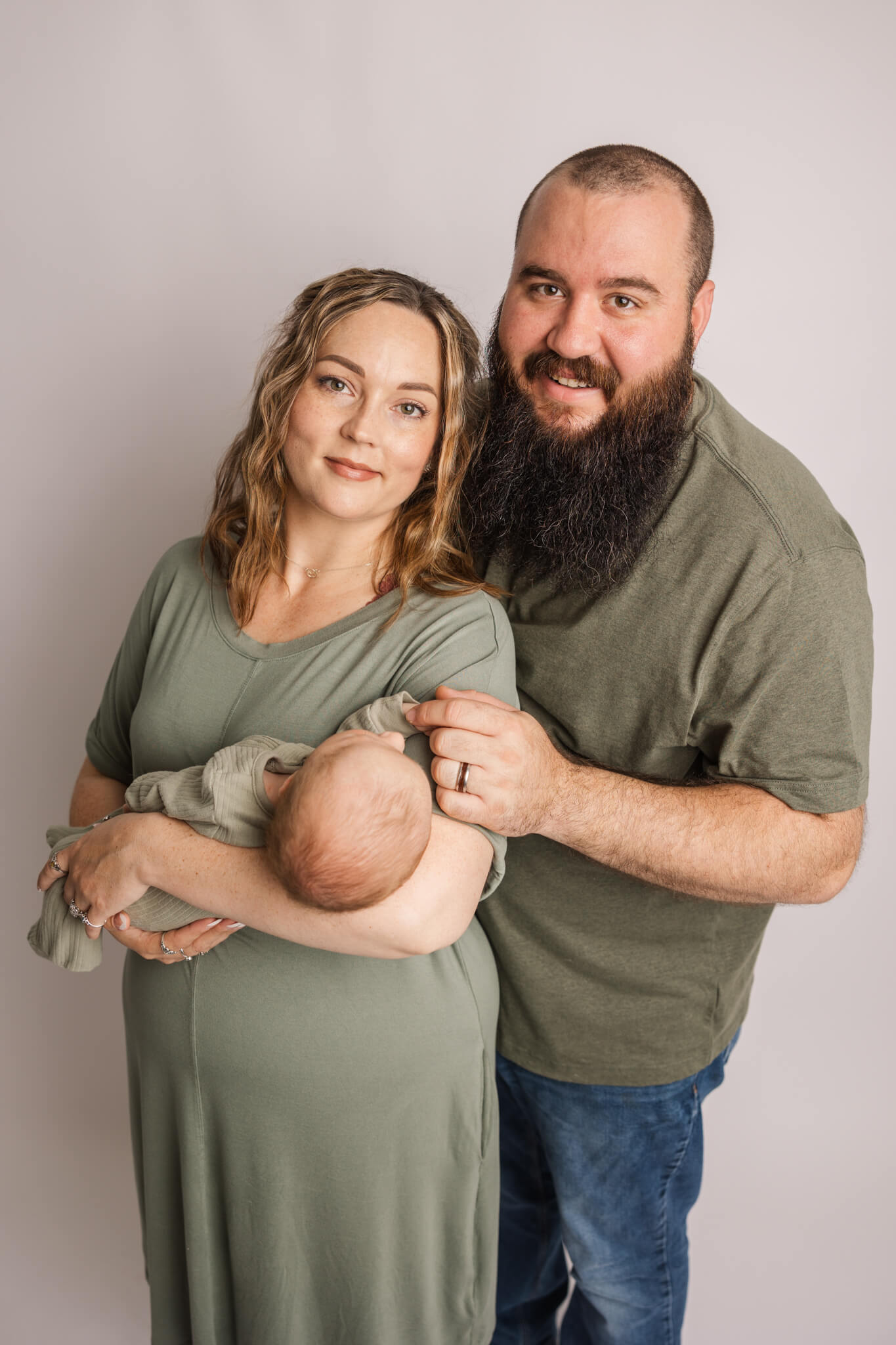 new mom and dad holding their newborn with everyone in green