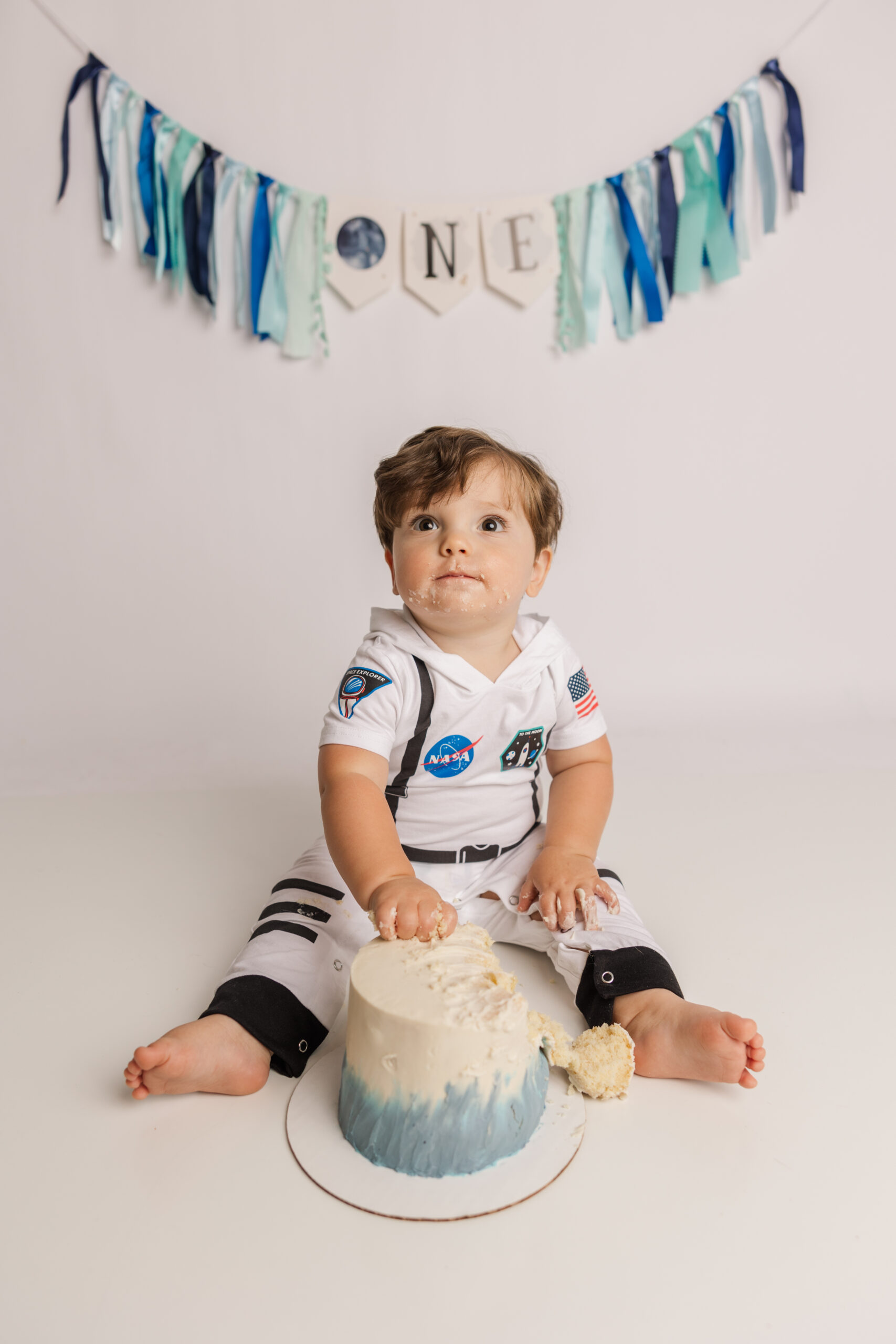 One year old enjoying his space themed cake smash during his recent one year celebration session.