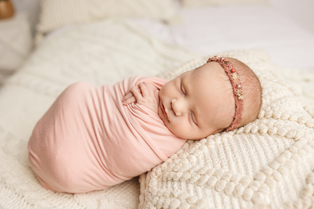 Newborn baby girl wrapped in pink wrap. Newborn session captured by Molly Berry Photography in the studio