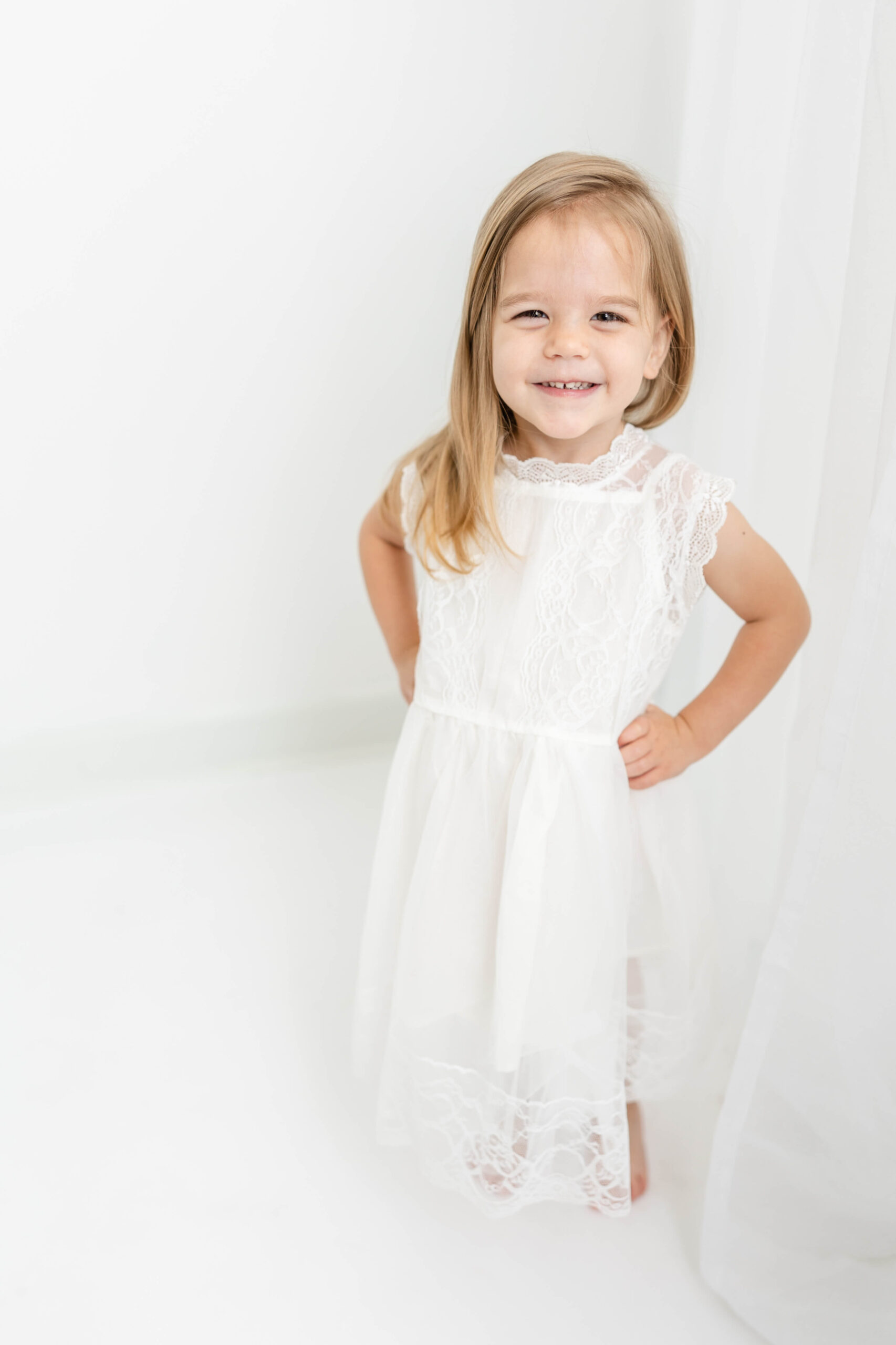 Captured smiling girl in white dress during studio session.