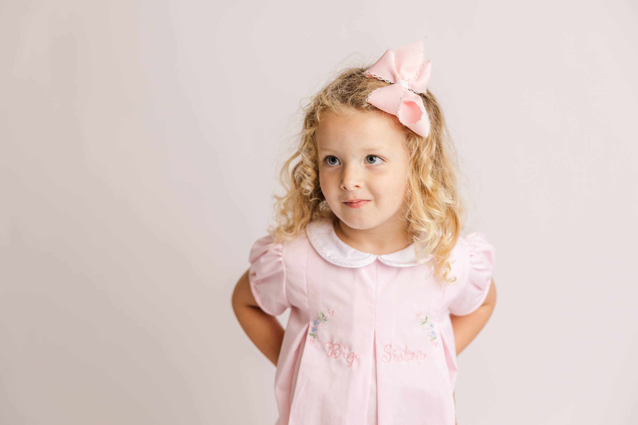 Little girl in pink dress and large bow looking off camera Augusta Cheer Academy