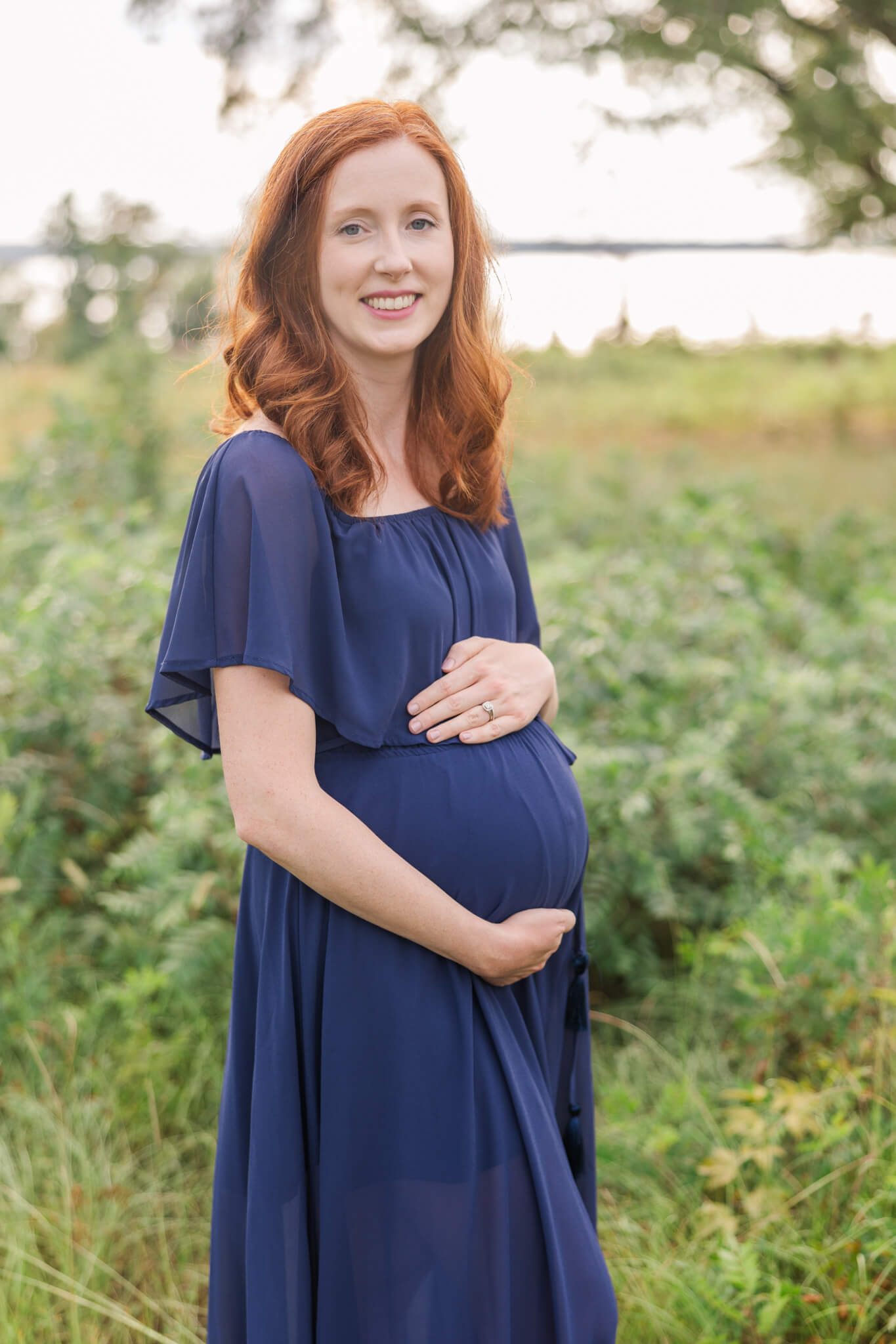 Expecting mom wearing a navy Baltic born dress during her maternity session captured near Clarks Hill Lake. Little Hands and Little Feet Doula