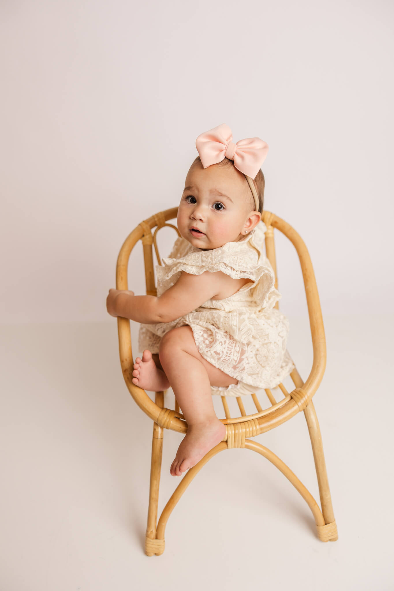 little girl with large pink bow playing in a chair