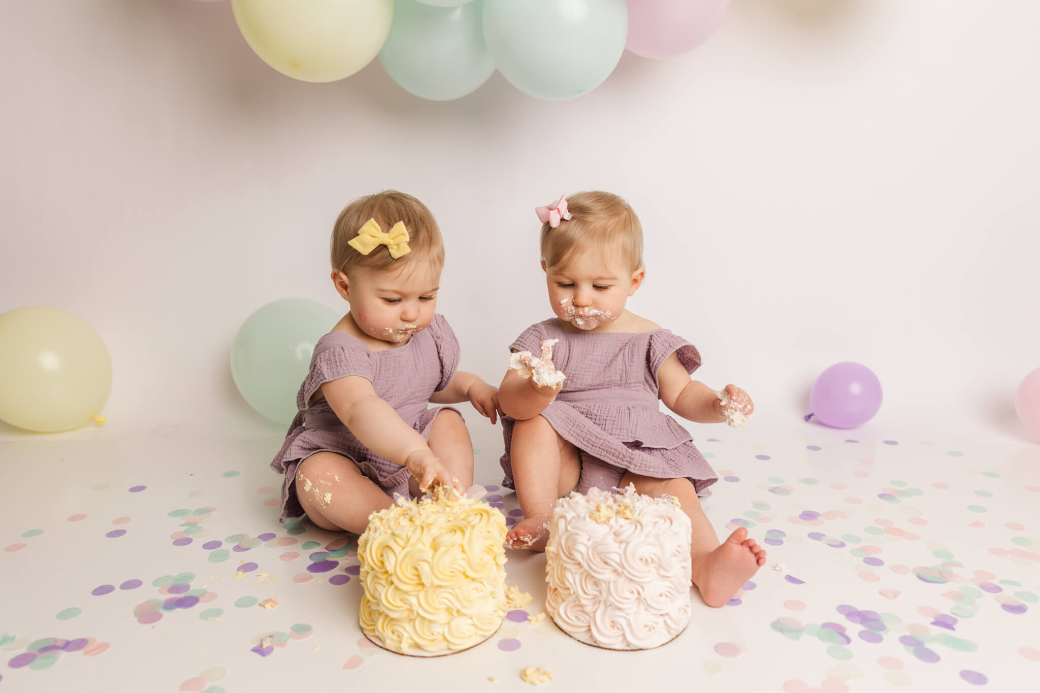 twin girls in purple dresses eating their first birthday cakes Center For Pediatric Dentistry