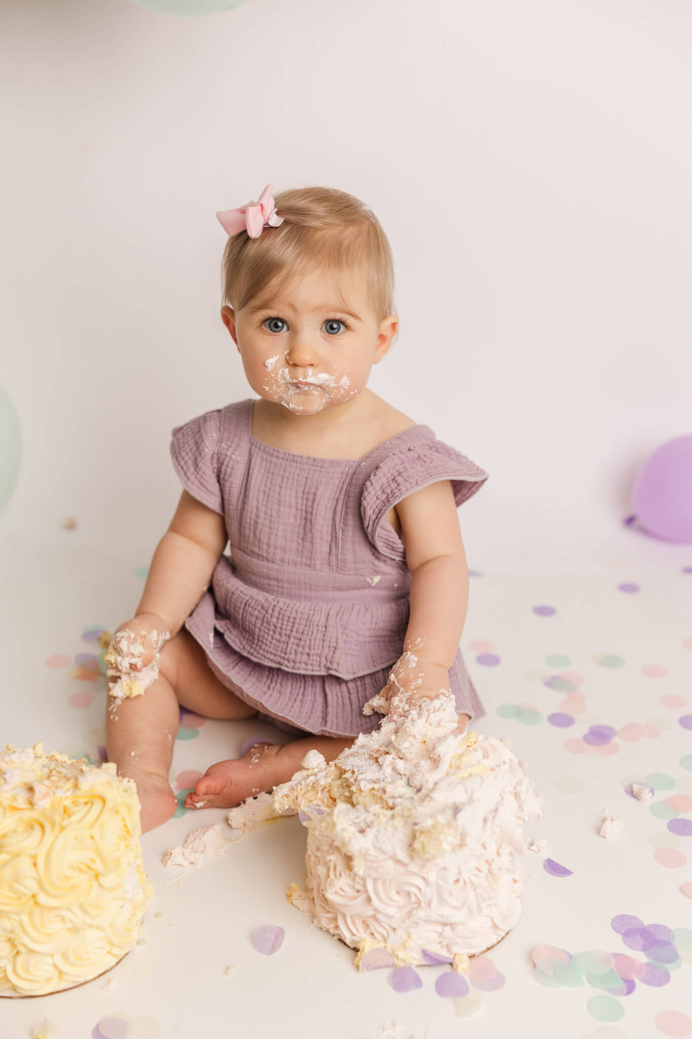 little girl in purple dress smashing her first birthday cake Center For Pediatric Dentistry
