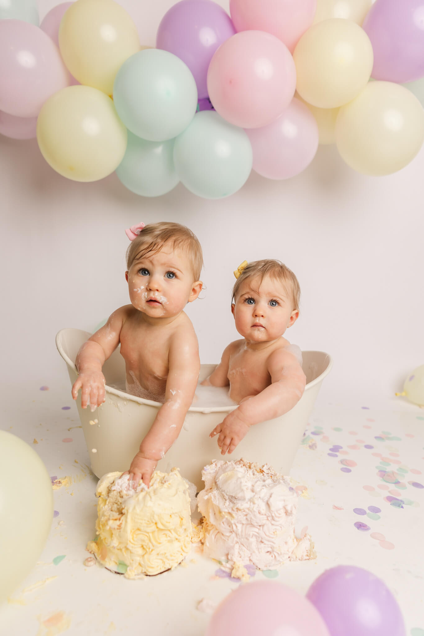 Twin girls sitting in a bathtub after a cake smash session Center For Pediatric Dentistry