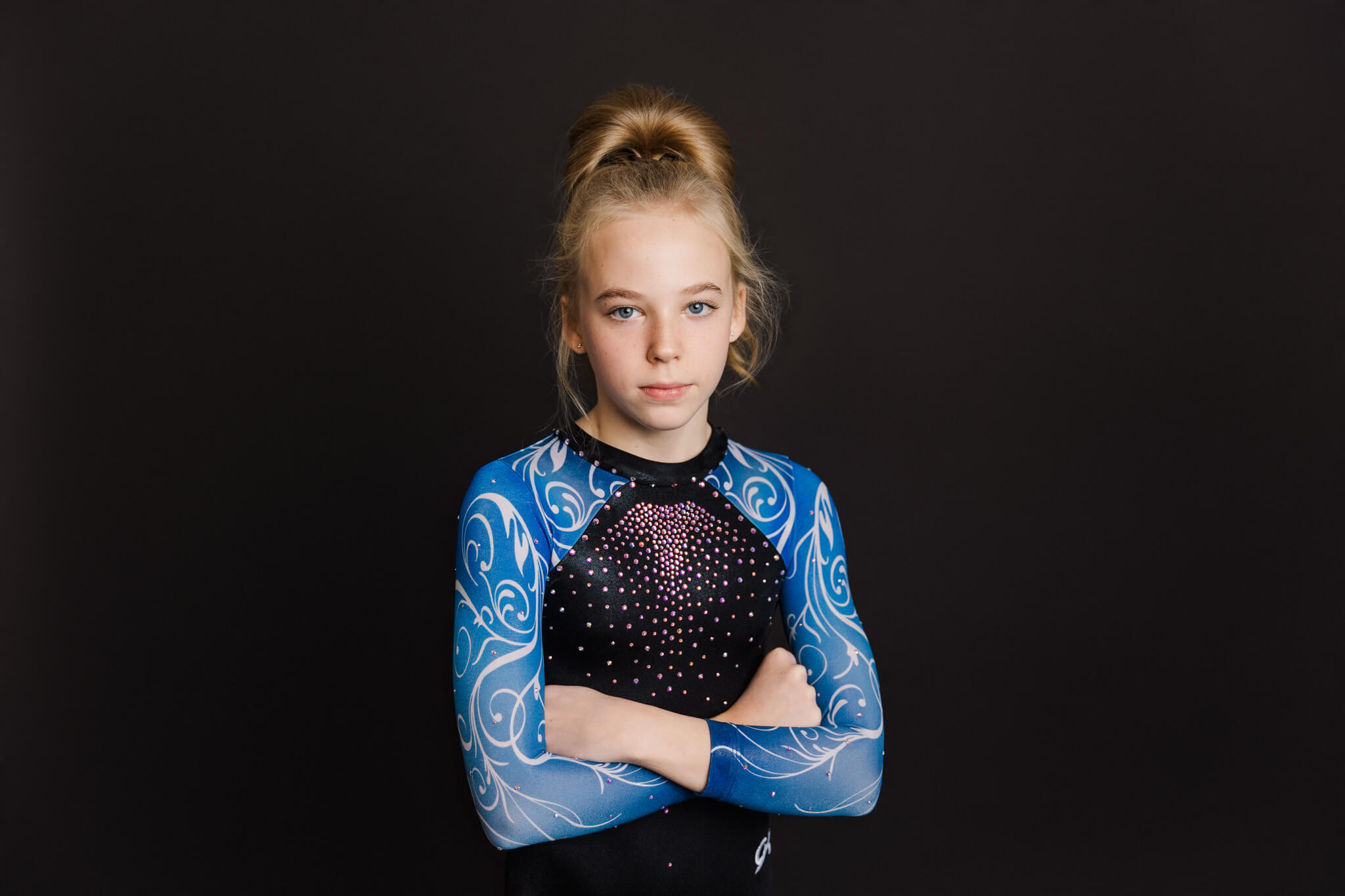 gymnast in blue and black leotard standing with her arms crossed Gymnastics Gold Augusta