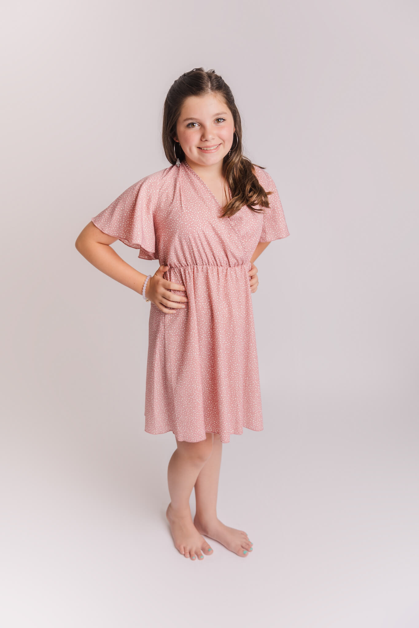 girl in pink dress posing on a white backdrop