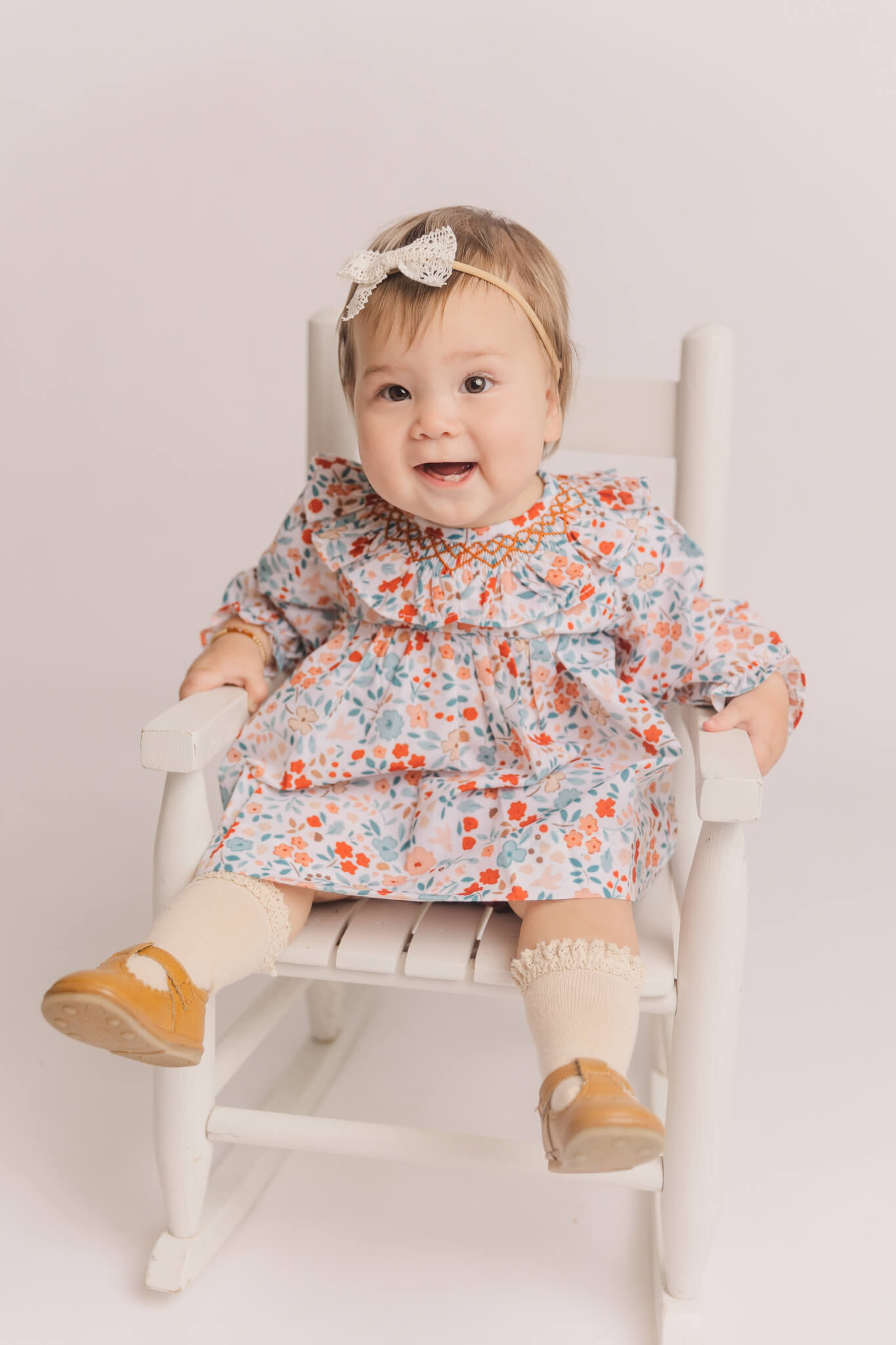 little girl in flowery dress laughing in a rocking chair