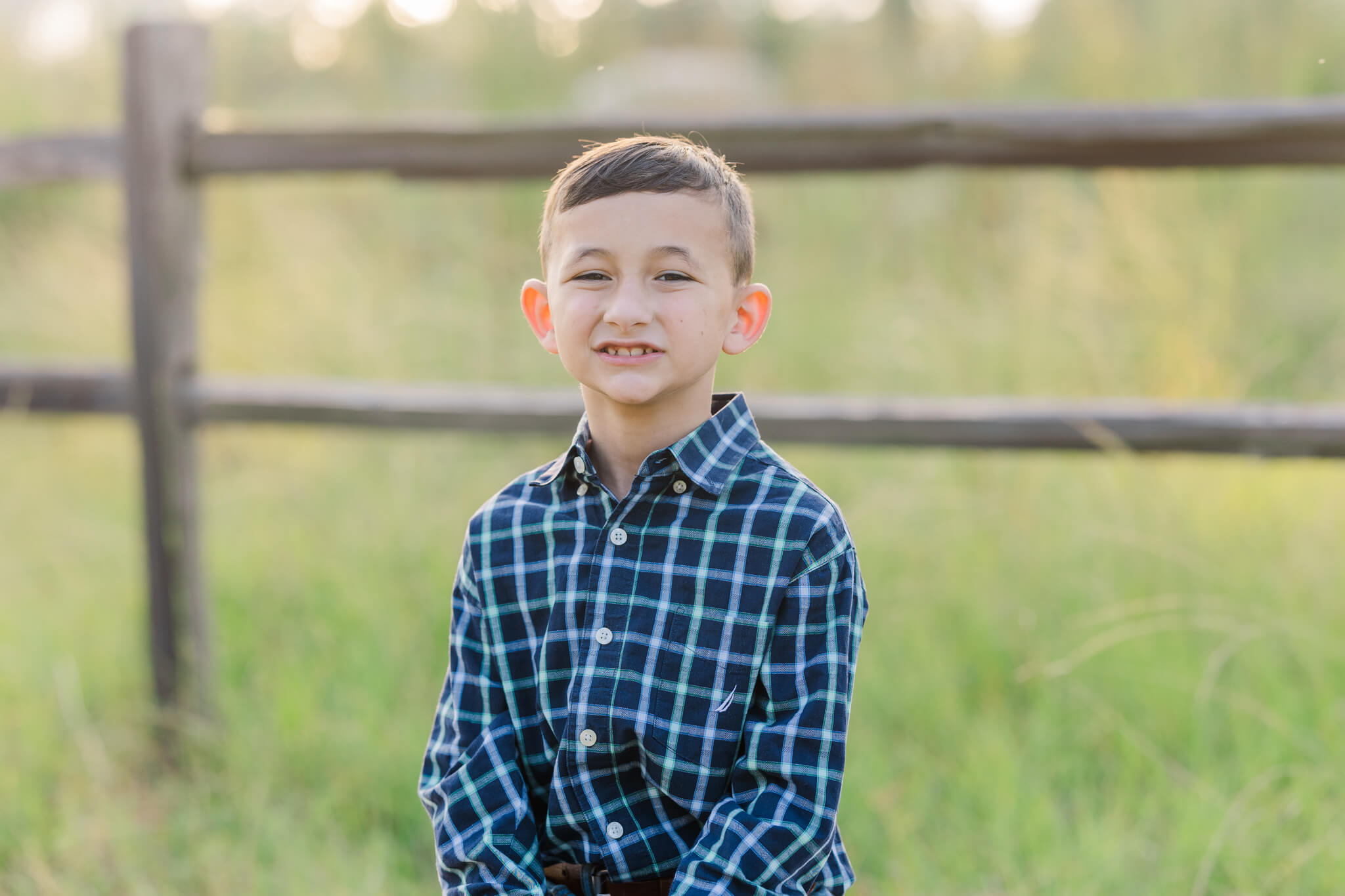 boy in blue plaid shirt standing in a field