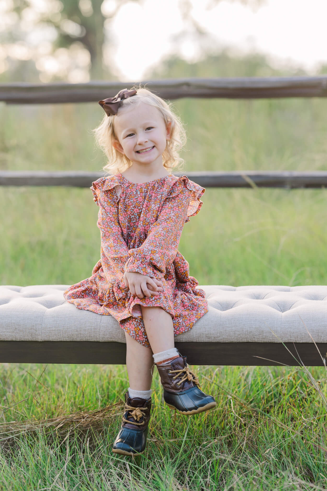 little girl in pink dress and boots sitting on a bench in a field Pediatric Partners of Augusta