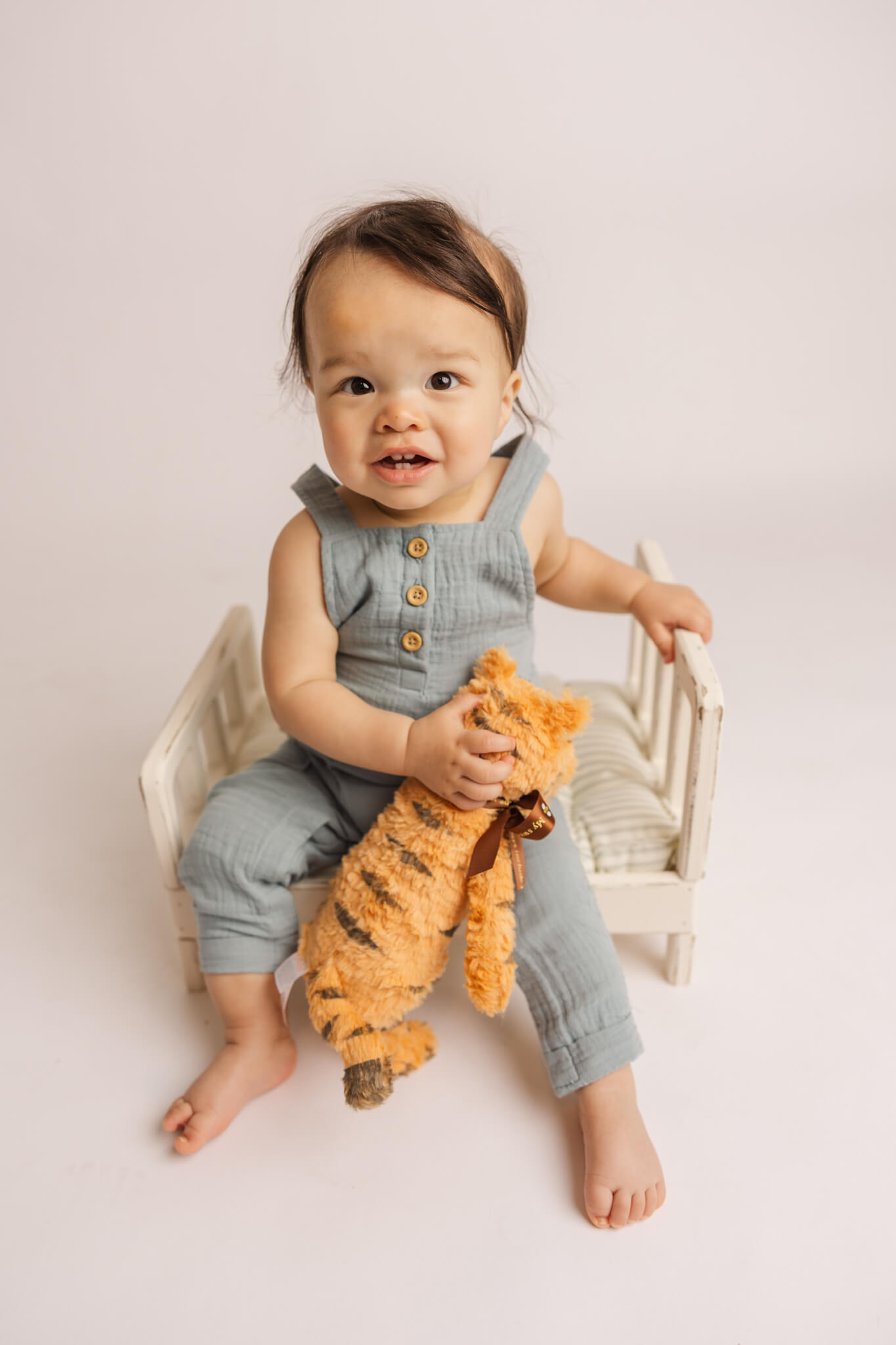 little boy in blue overalls holding a stuffed animal