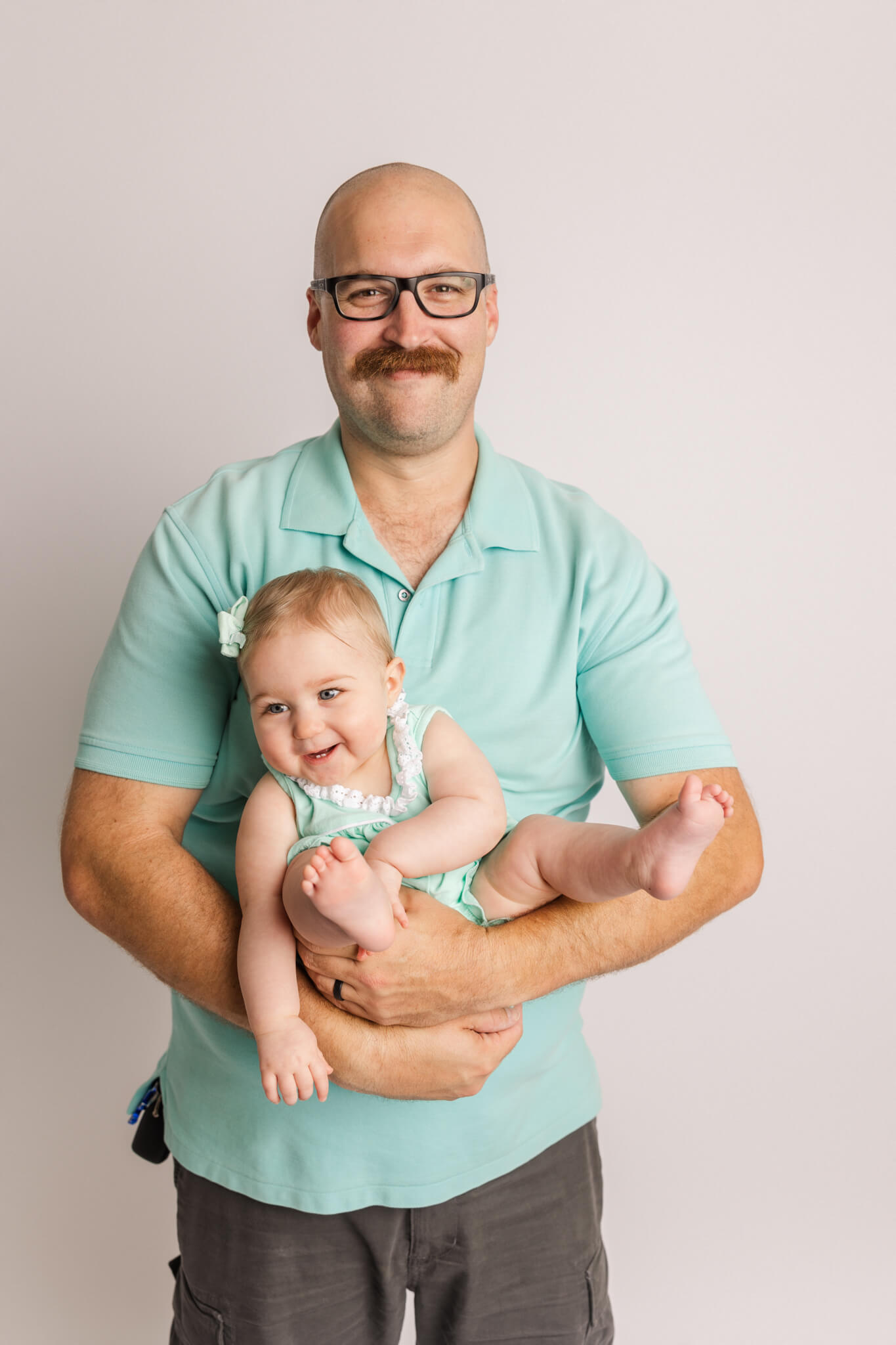 new dad in teal holding his daughter in matching colors