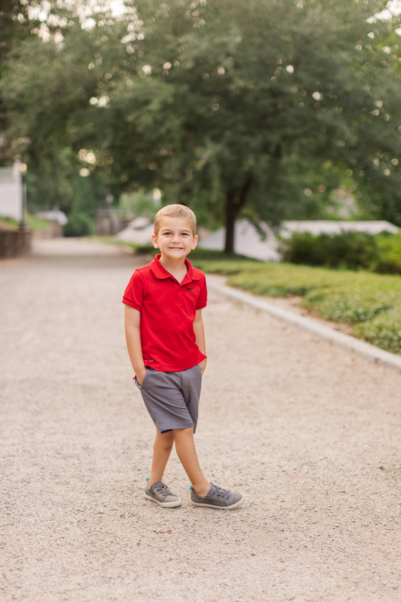 little boy in red polo and grey shorts standing in the street