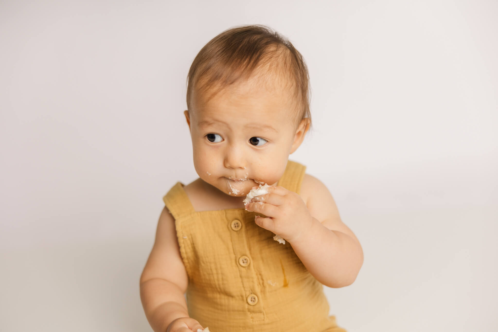 Little boy enjoying a bite of cake during cake smash session.