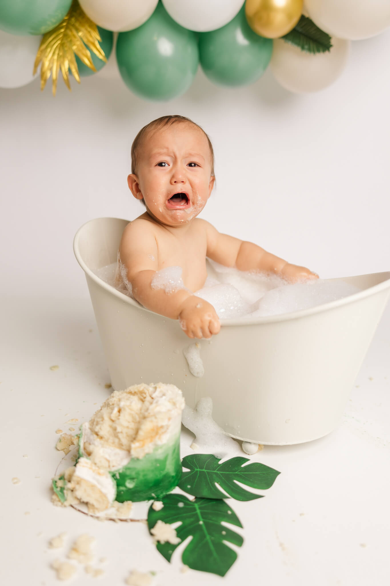 One year old displeased with clean up in bath after cake smash session with Molly Berry Photography.