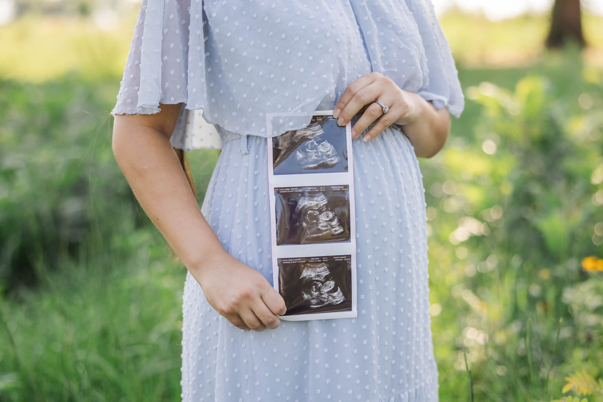 Pregnant mom in blue dress holding sonogram picture