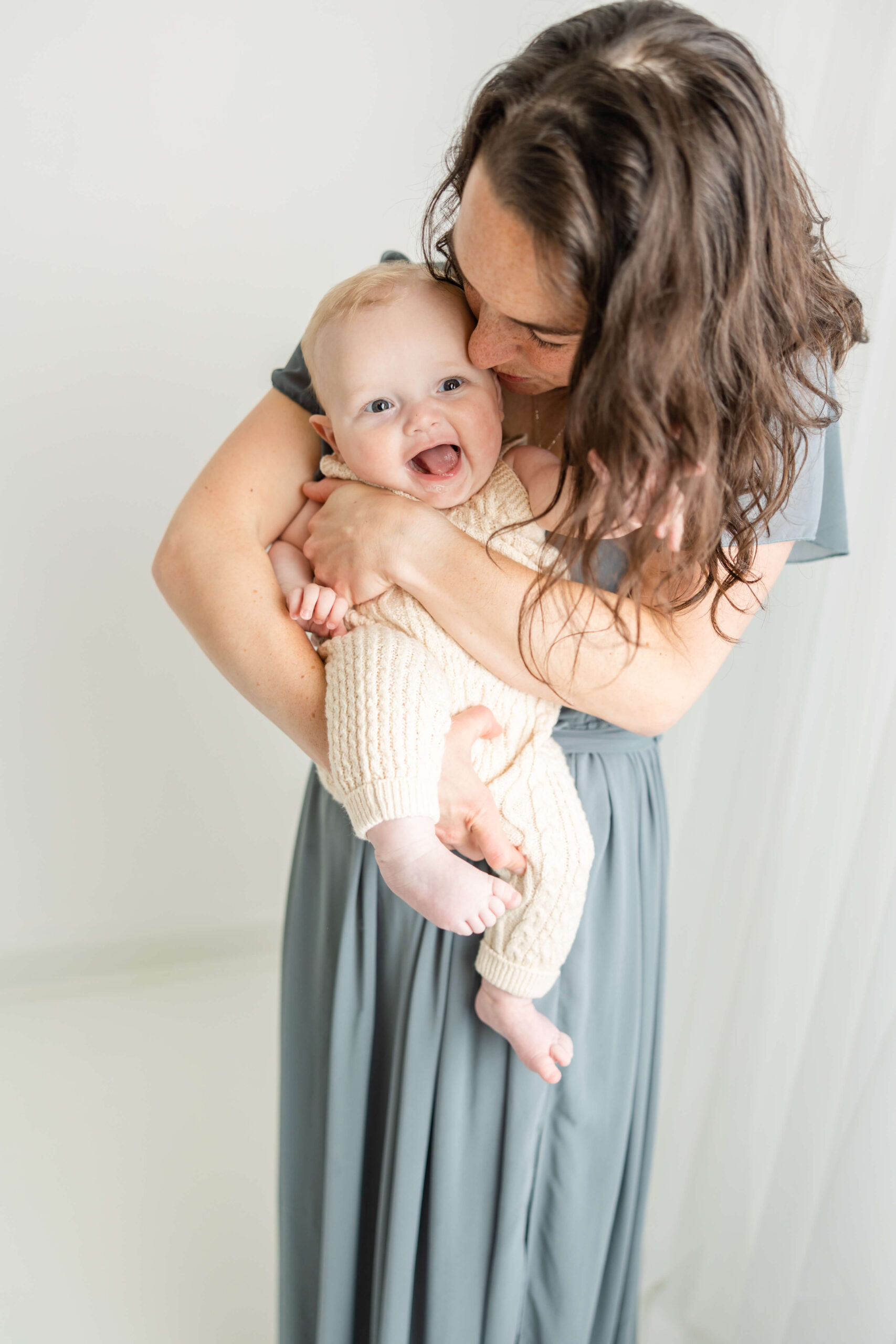 Mom in full length blue gown and her baby boy wearing a cream jumper, both from client closet for their motherhood session with Molly Berry Photography.