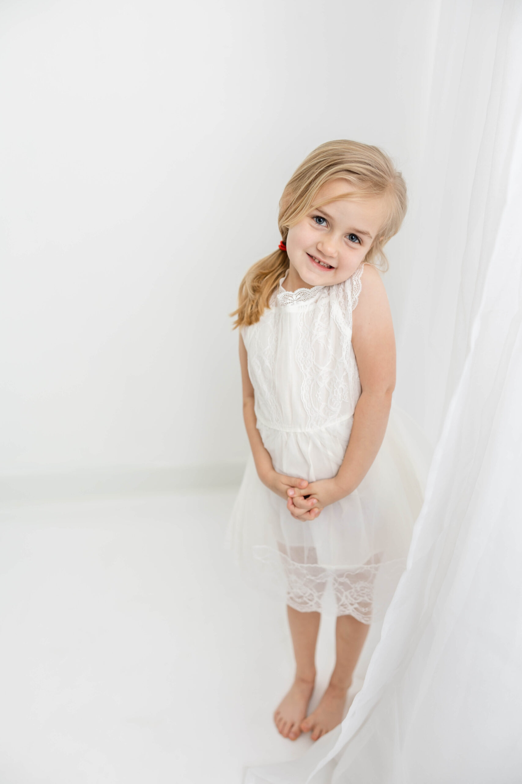 Full length shot of 4 year old girl in white lace dress. 