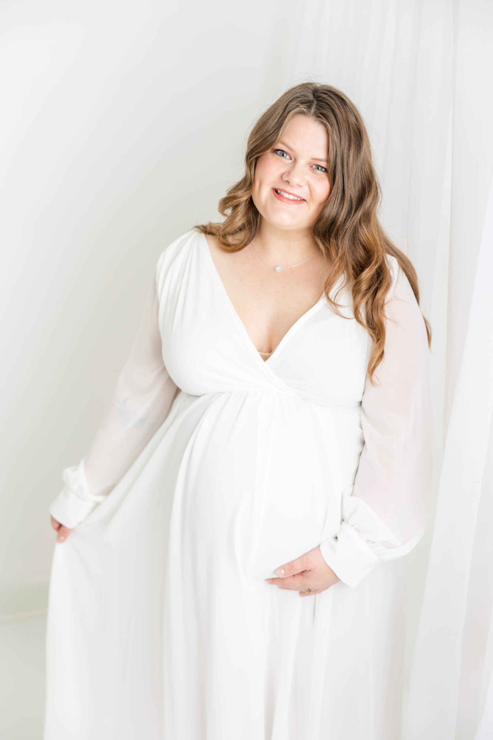 Captured soon-to-be mom wearing a flowing white gown during her maternity session with Molly Berry Photography.