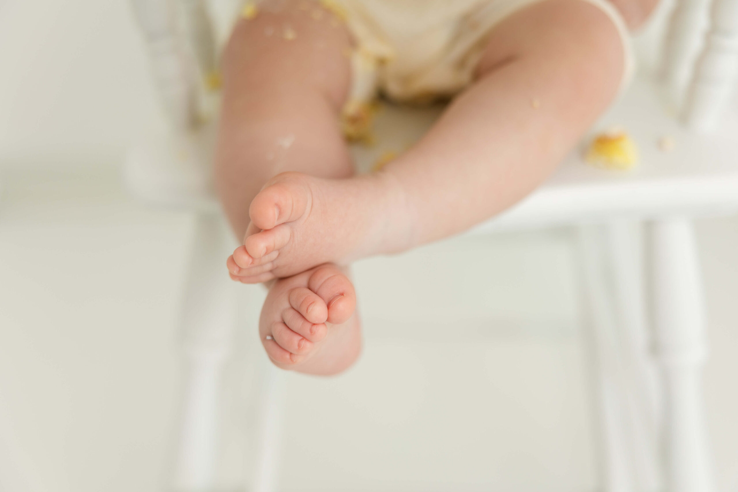 Close up image of baby boy toes, with just a little cake all around him.  