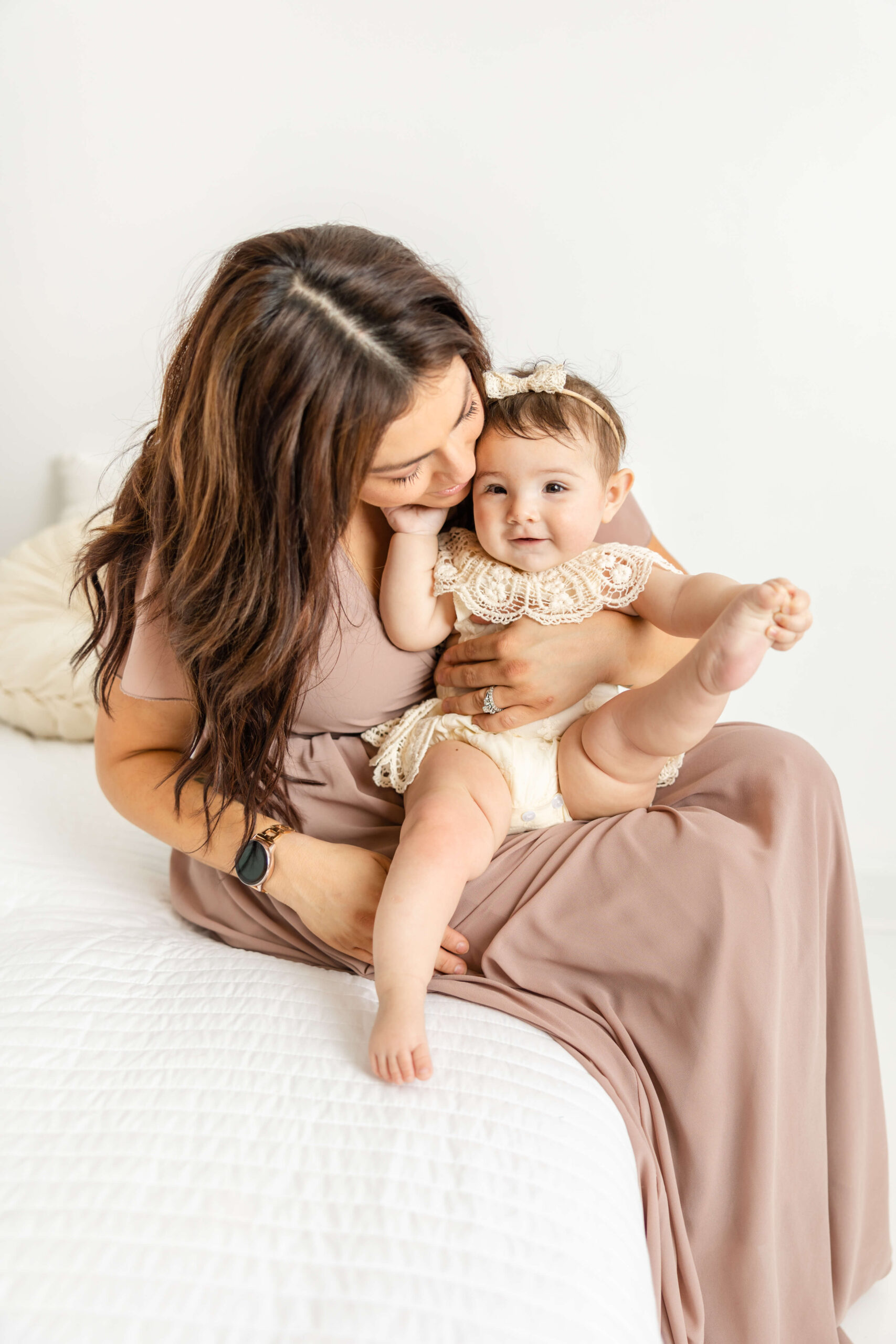 Mom and her sweet girl sitting on a bed during their motherhood session.