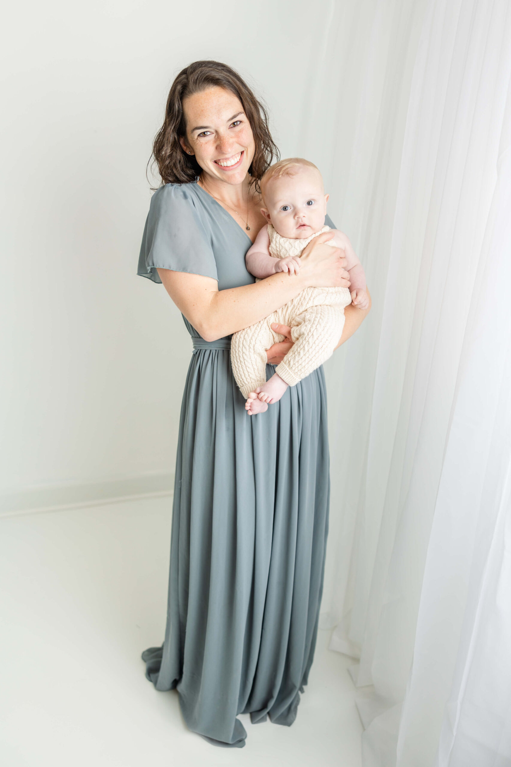 Mom in full length blue gown and her baby boy in cream romper, both from client closet for this motherhood session. 
