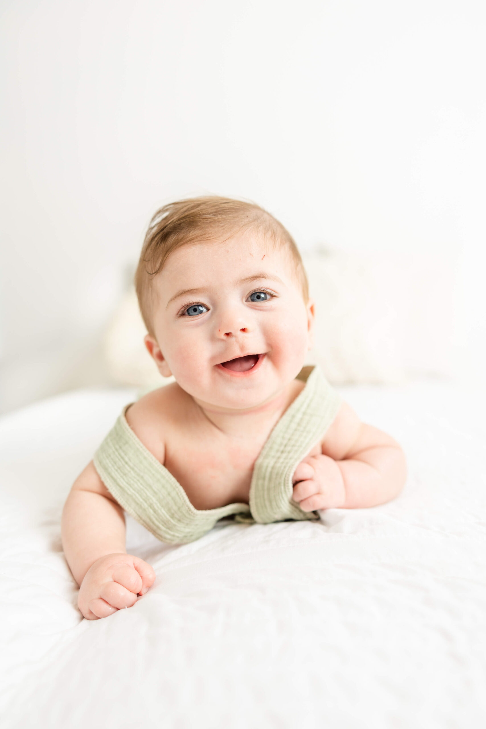 Baby boy laying on his tummy on white bed during family session with Molly Berry Photography.