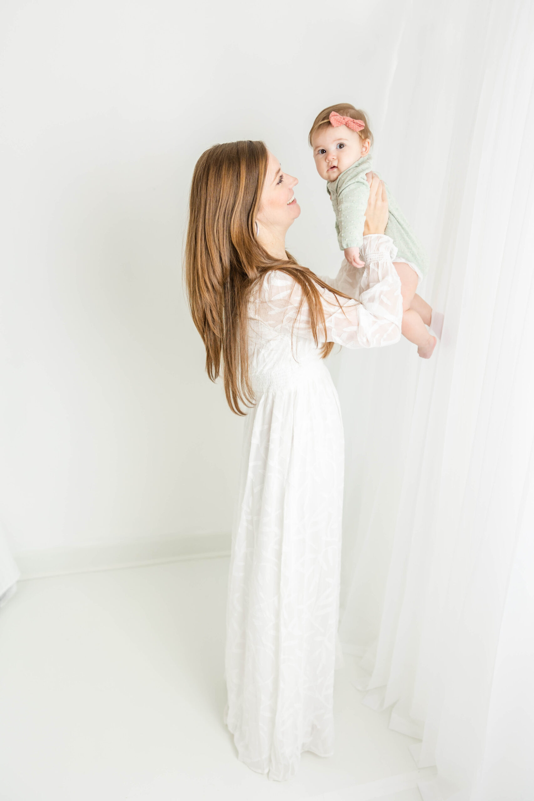 Captured full length side view of mom holding her baby girl during their motherhood session.