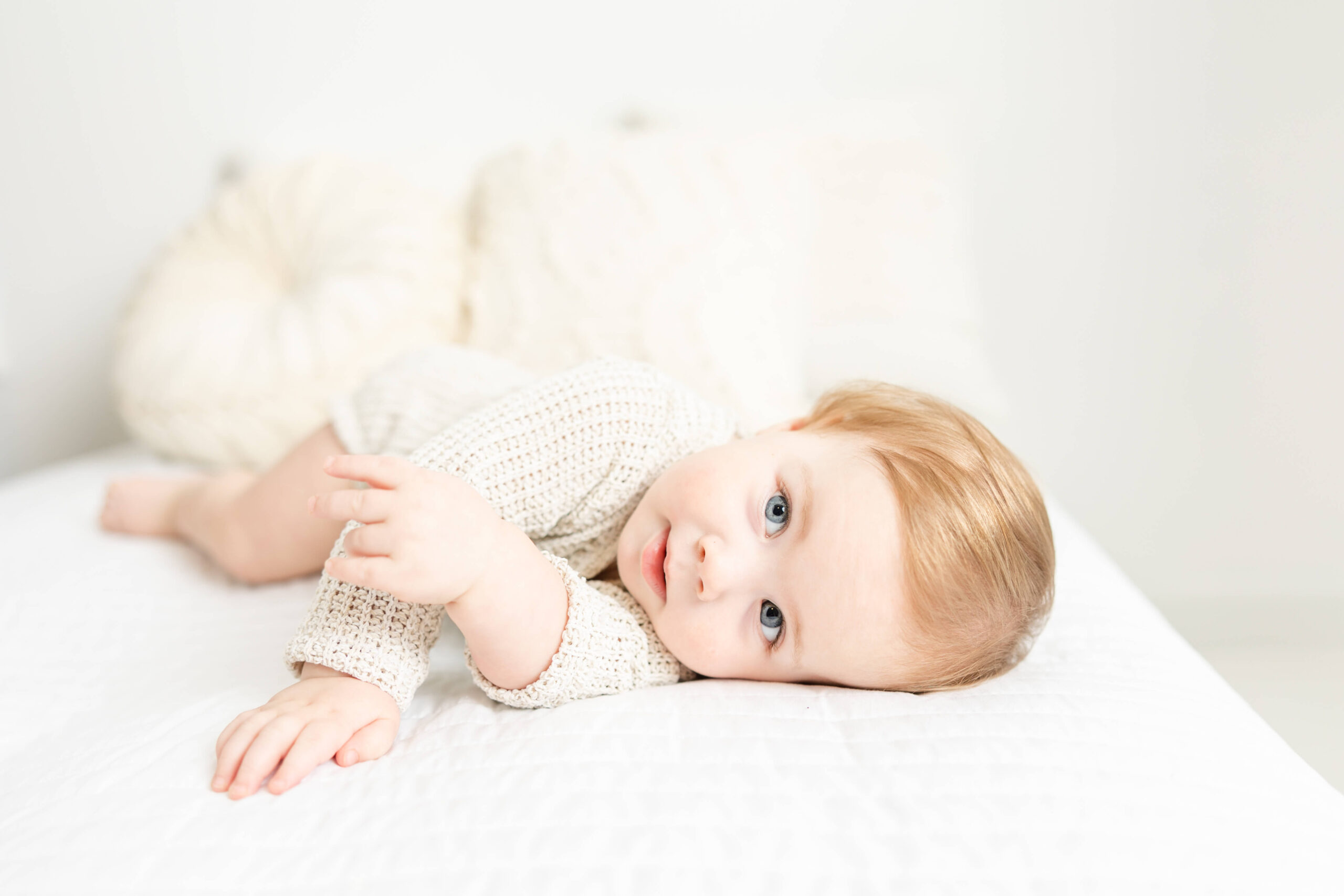 One year old laying on bed during his milestone session in the studio of molly berry photography.