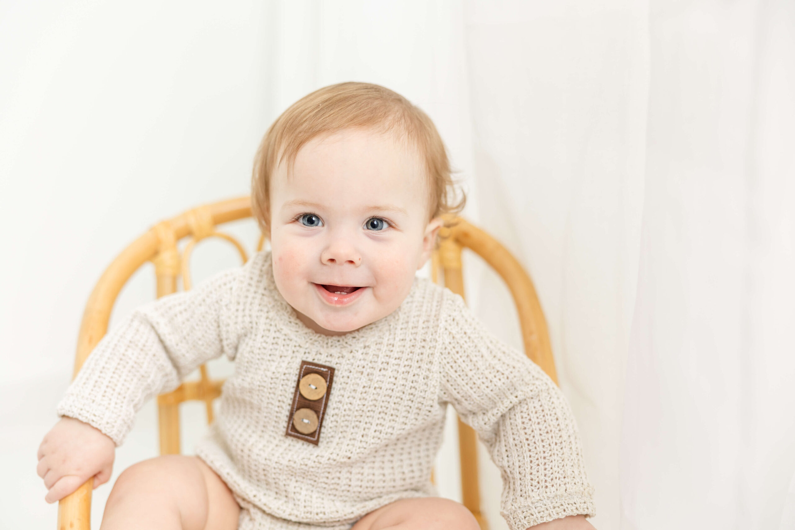 Close up of one year old sitting in wicker chair during his milestone session.