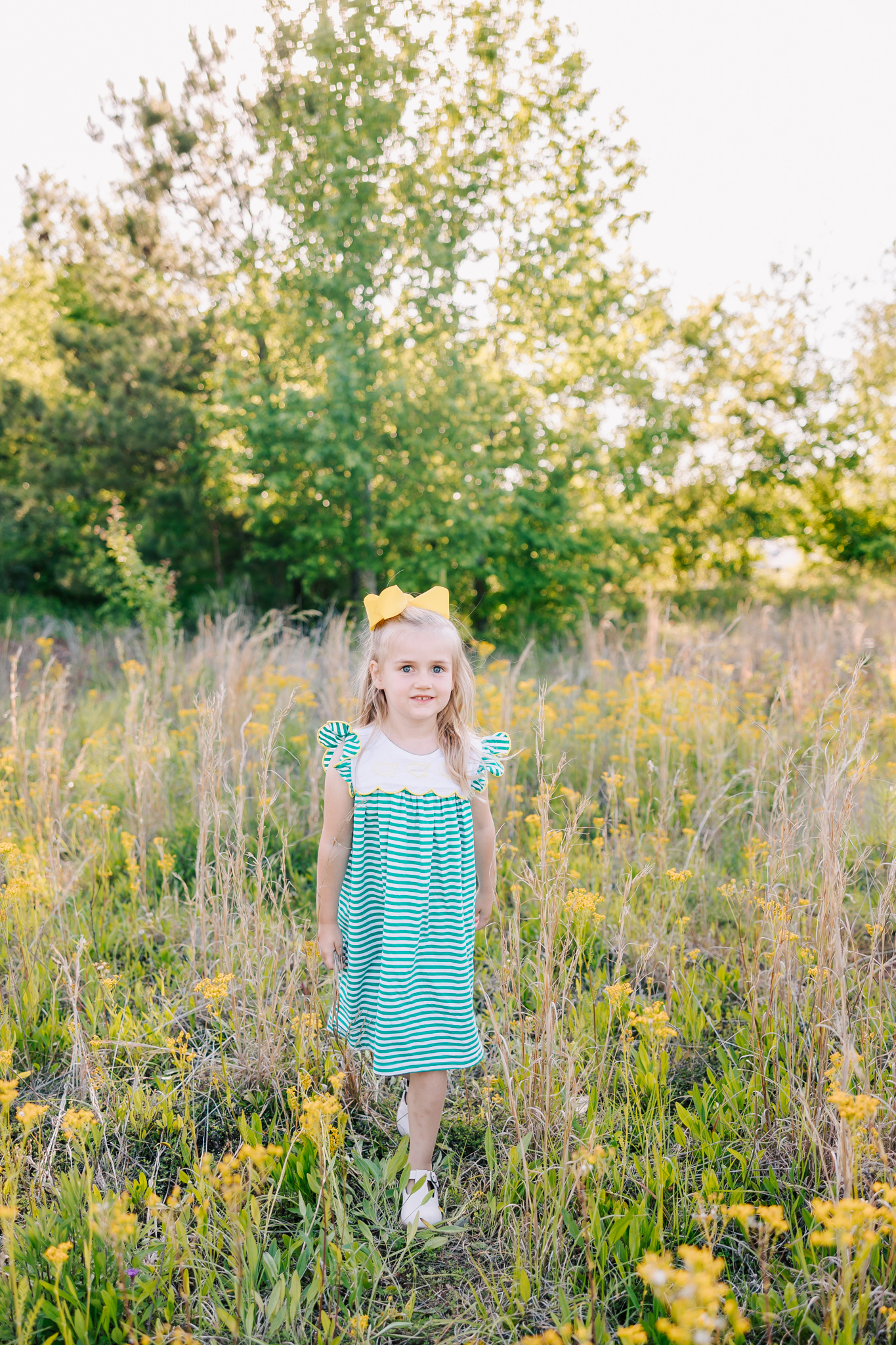 School aged girl walking through an open field with yellow flowers.