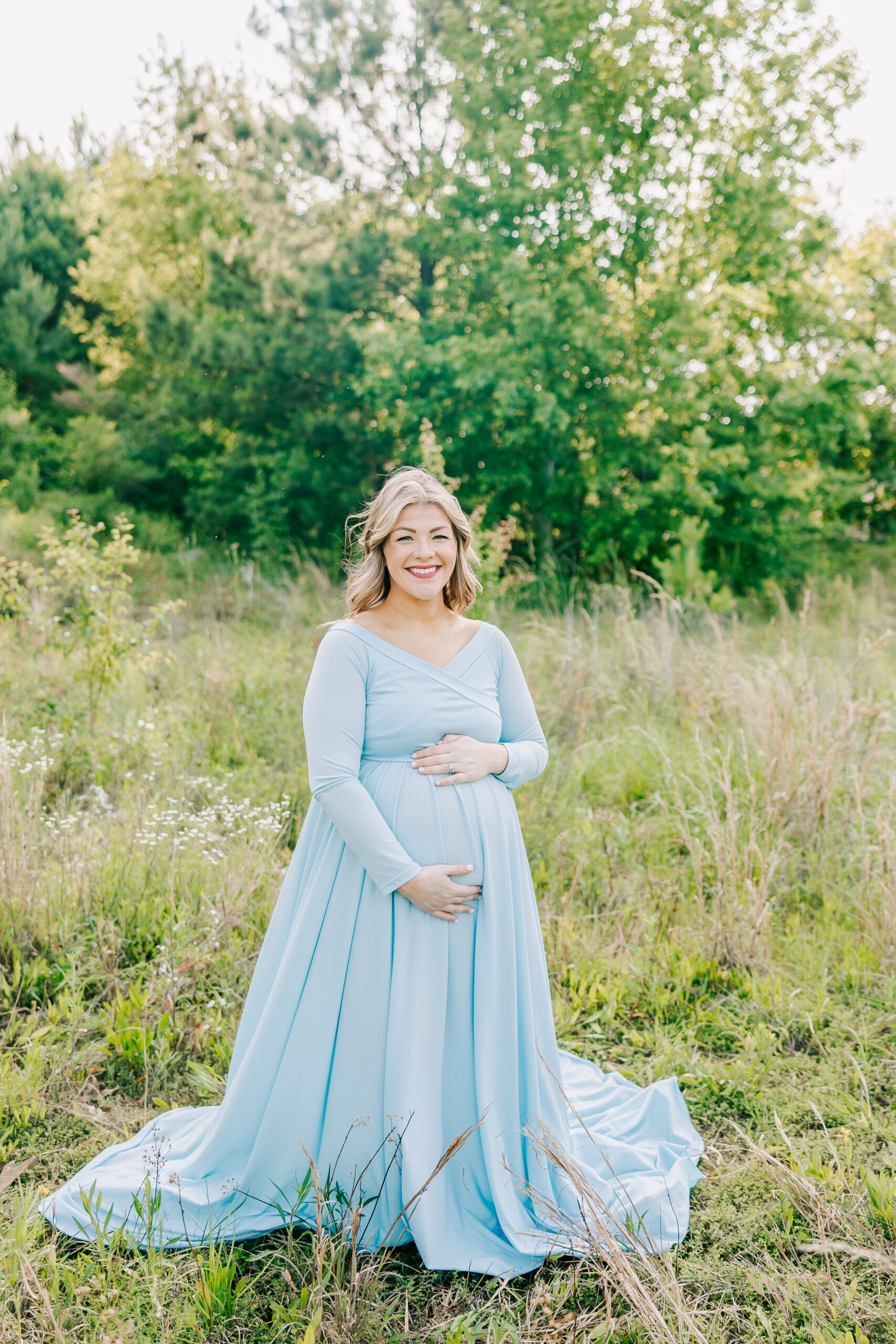Expecting mom smiling holding her belly during her maternity session.