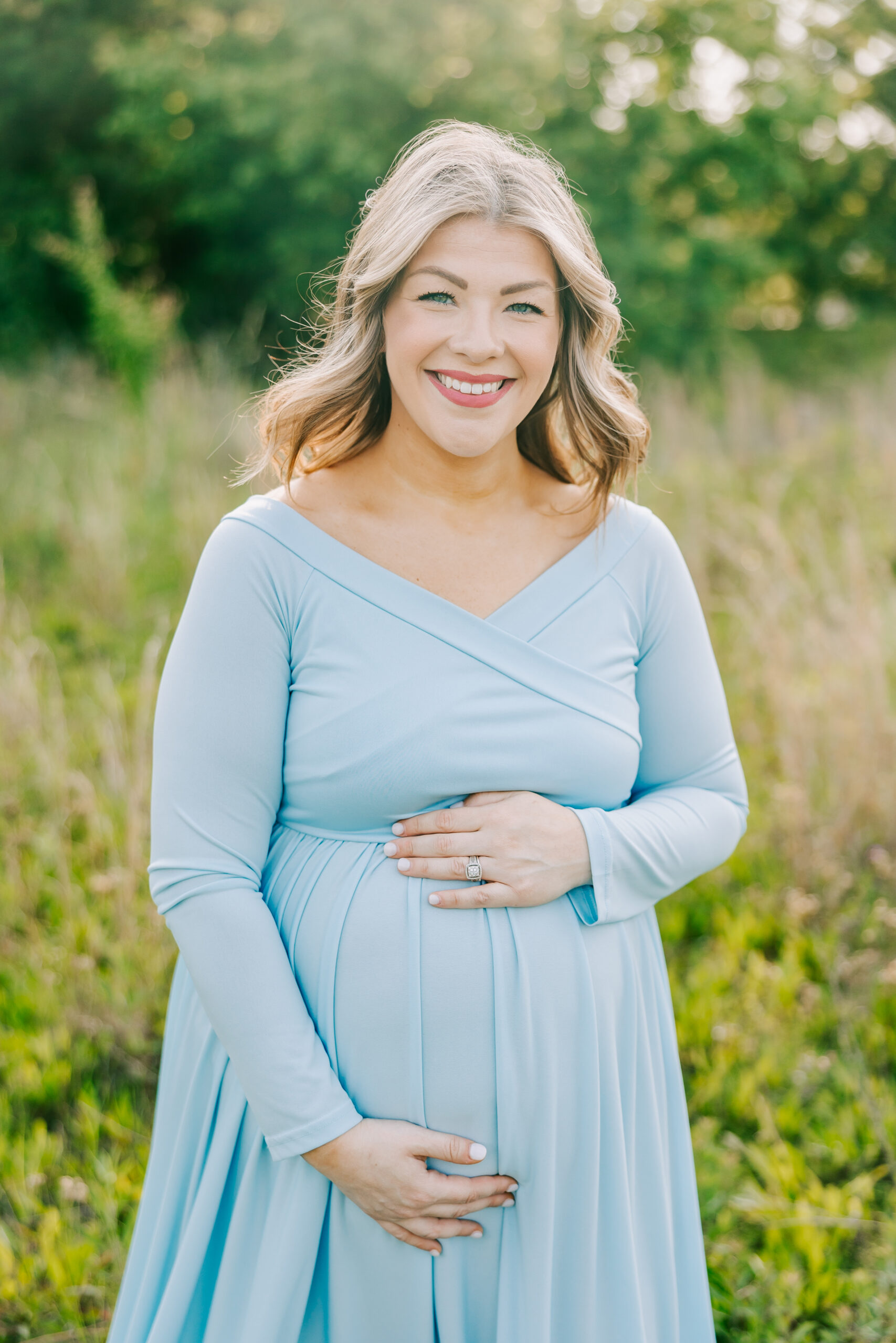 Expecting mom holding her baby bump during her session in an open field.