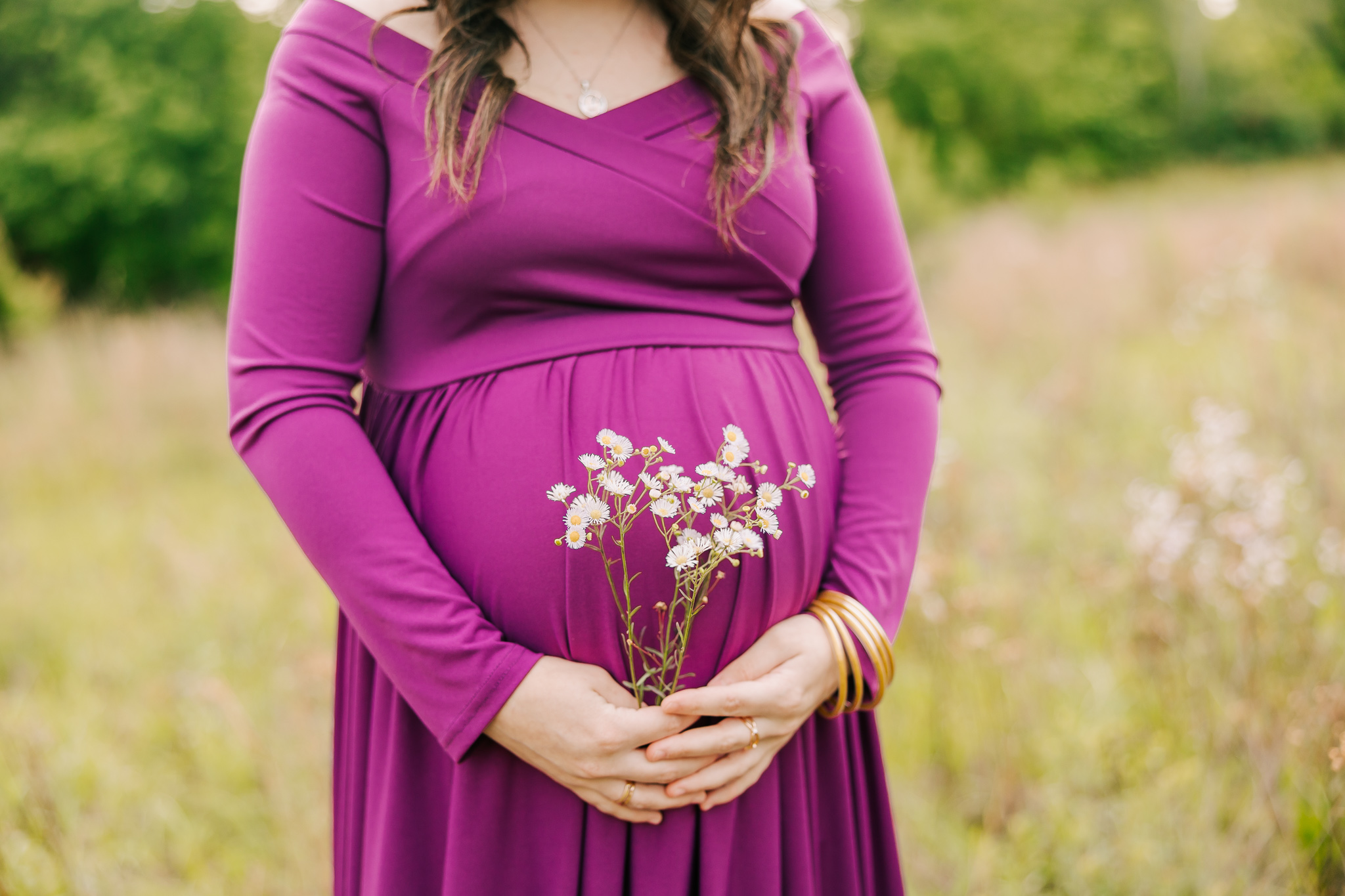 Close of of mamas baby bump holding flowers during her session.