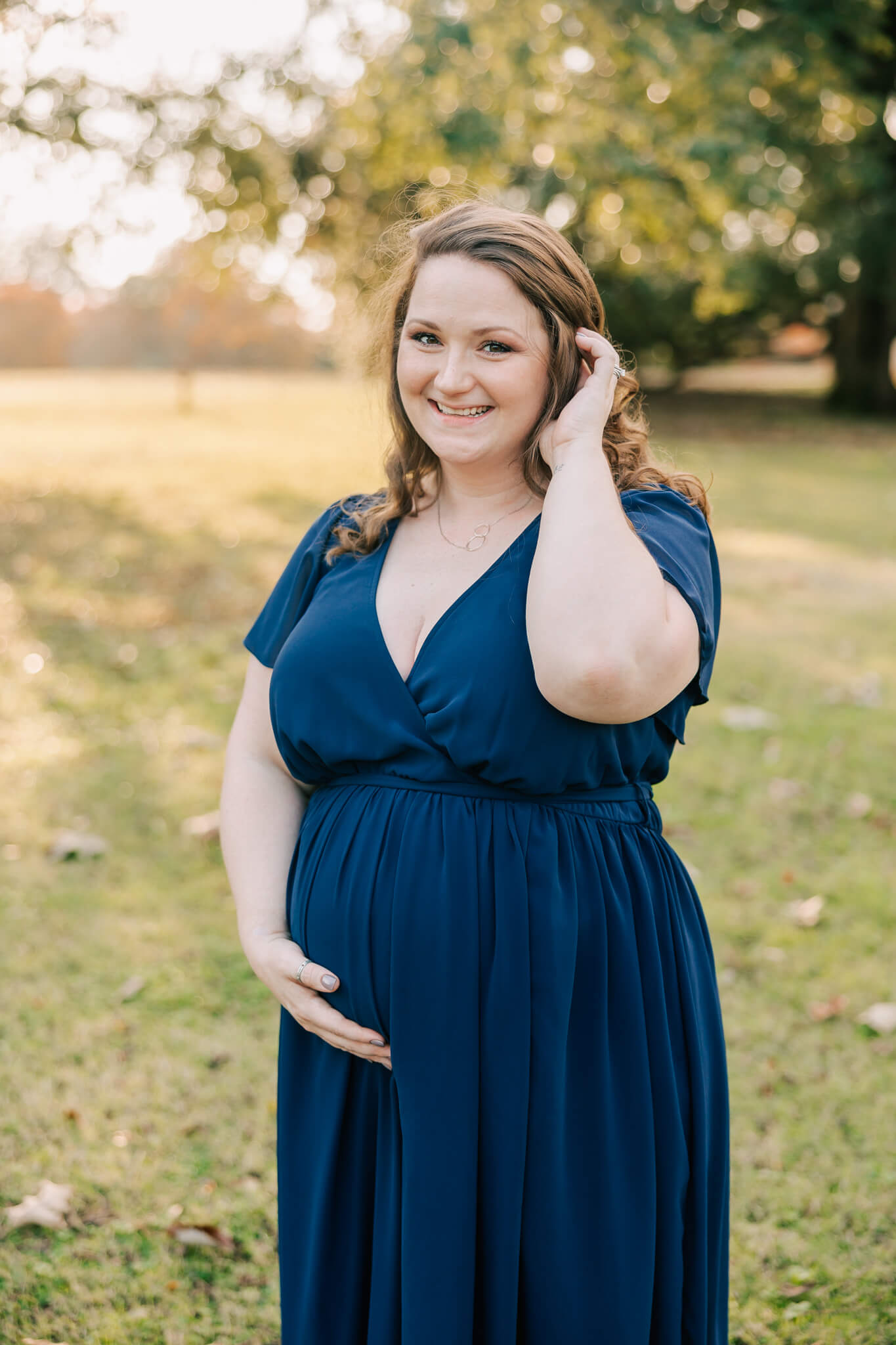 Expecting mom sharing a laugh during her maternity session in columbia, sc. Mom is wearing a navy blue dress provided by molly berry photography.