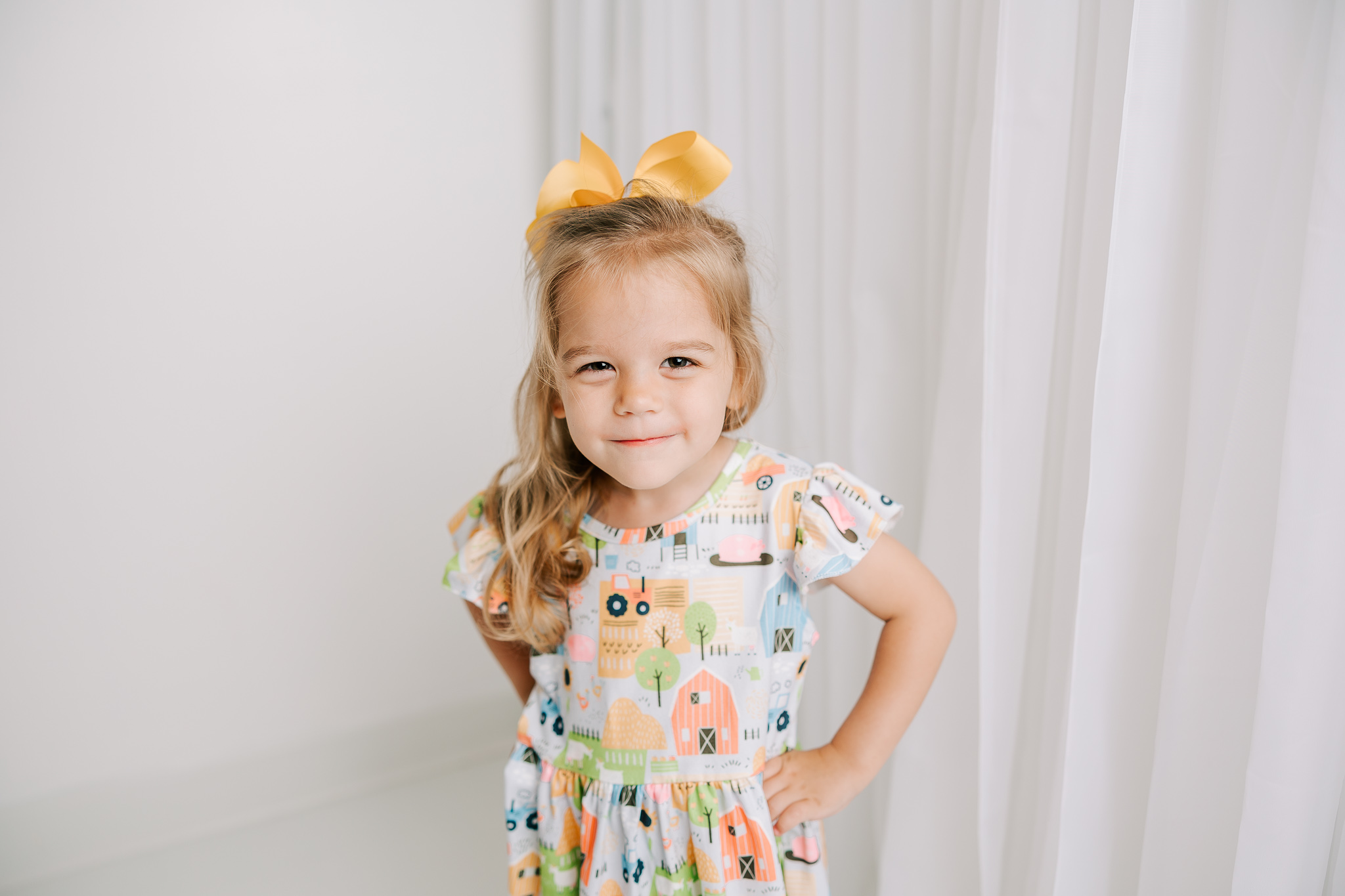 Three year old girl showing off her new Pete & Lucy dress from Sunshine Savvy Children's Boutique.