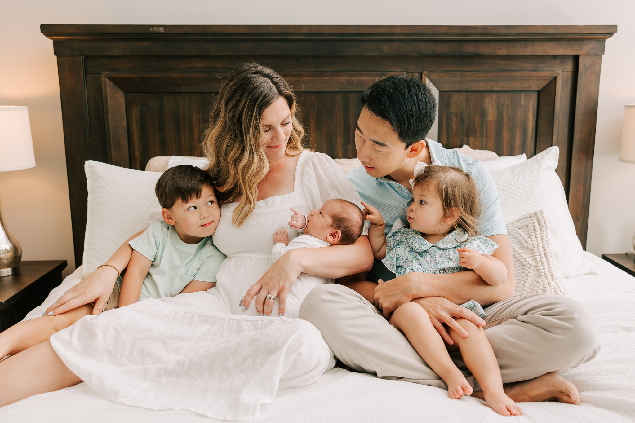 Family snuggling on their bed during their inhome newborn session with molly berry photography in columbia, sc.